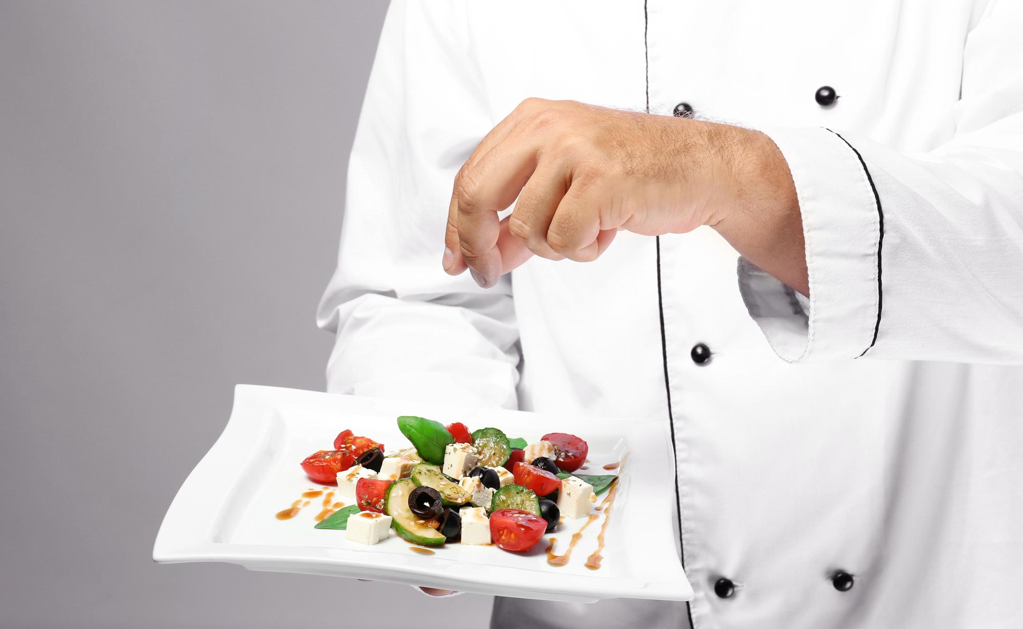 Chef preparing plated catering dish in modern kitchen